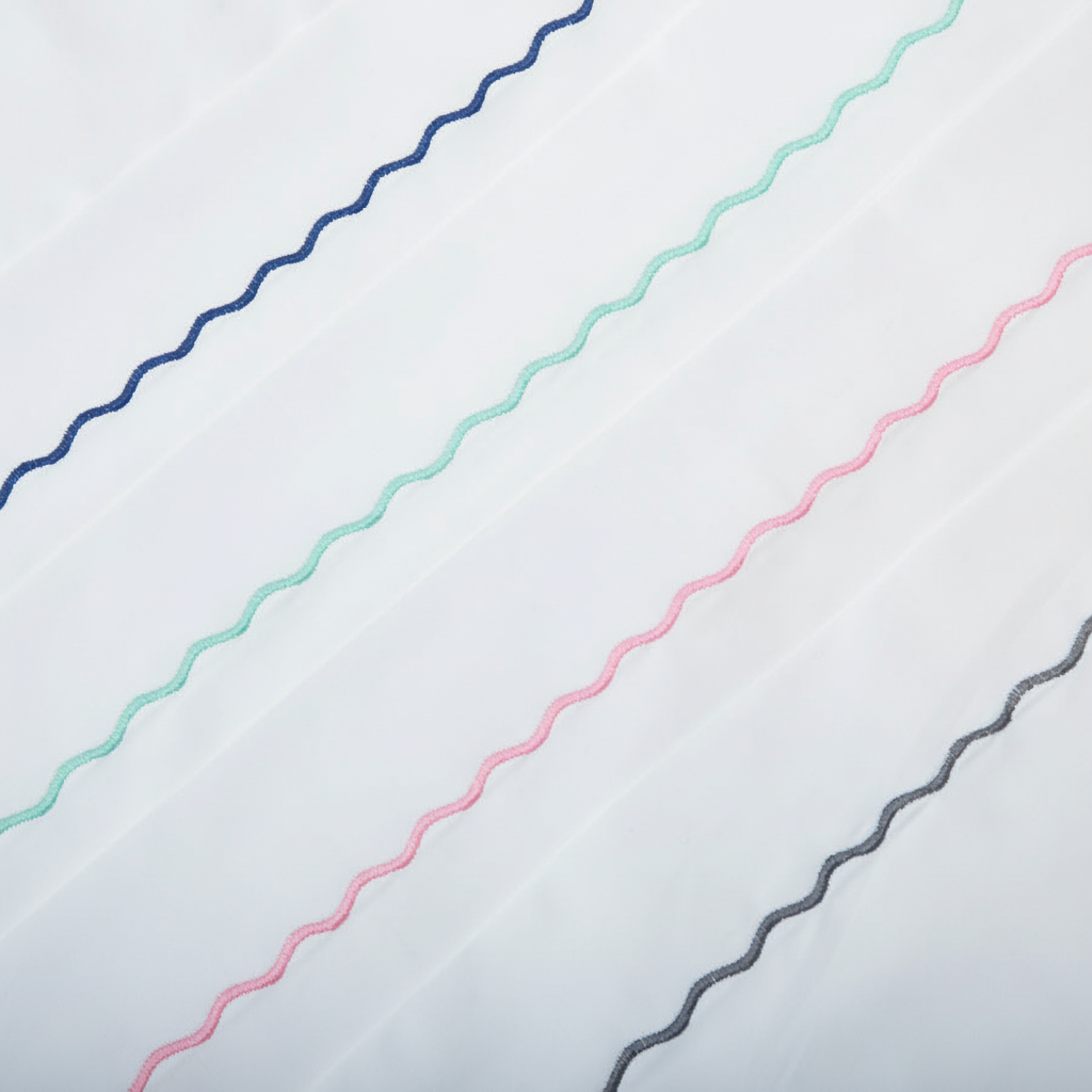 Classic Ric Rac embroidery detail showing dark blue, mint green, pink and grey wave stitch on cool bright white cotton percale